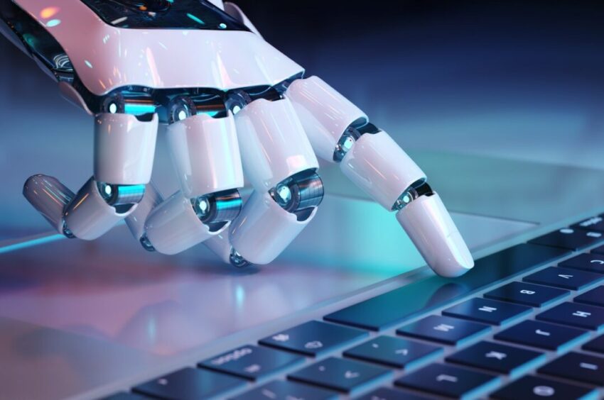 A robotic hand with glowing blue lights is about to press a key on a laptop keyboard.