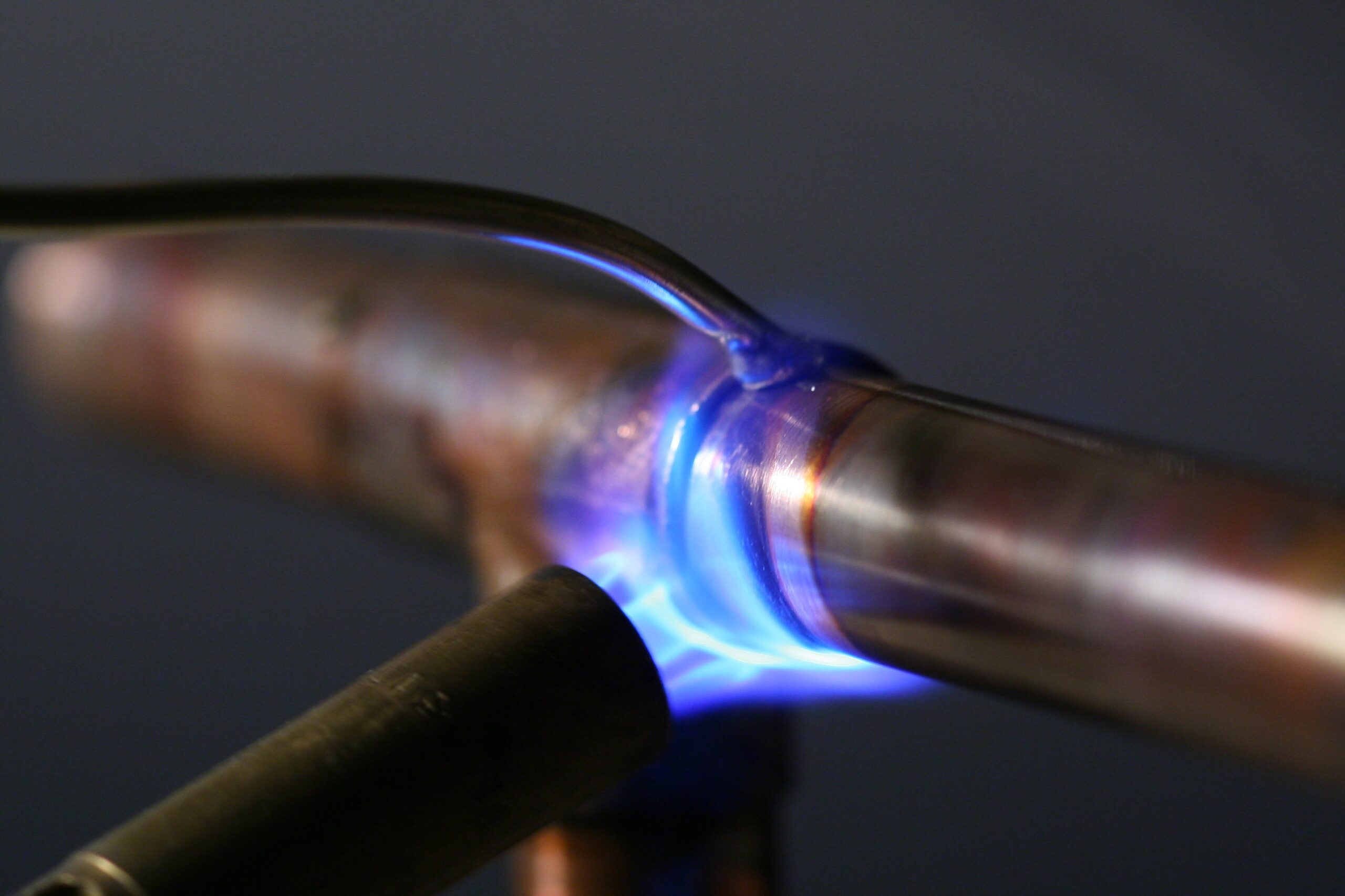 Close-up of a blue flame welding copper pipes.